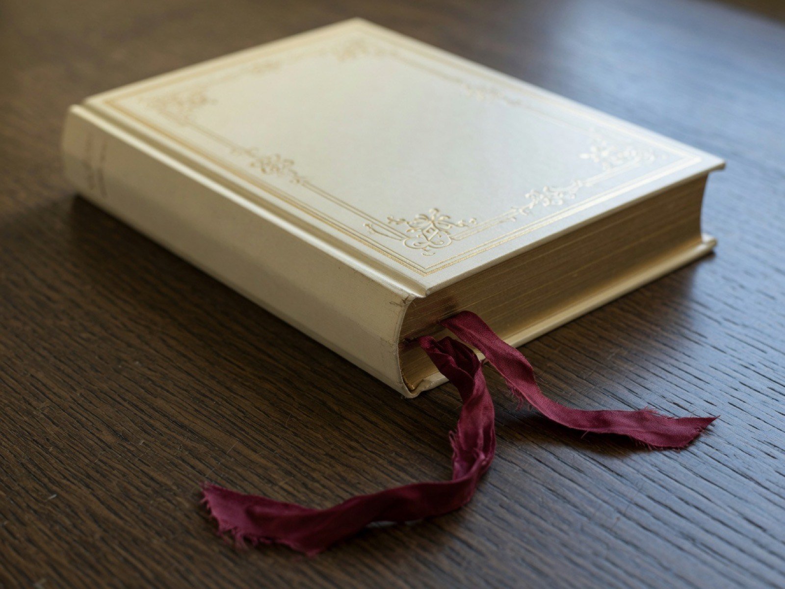 A cream hardcover with a burgundy ribbon